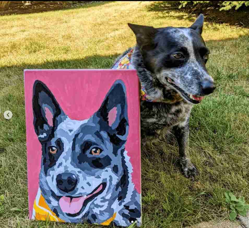 Dog standing next to a painted portrait of itself on a pink background