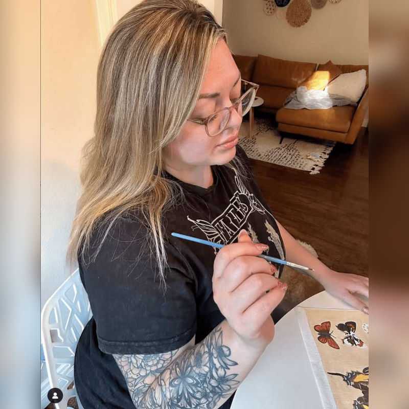 A lady holding a brush and painting a paint by numbers canvas in Canada