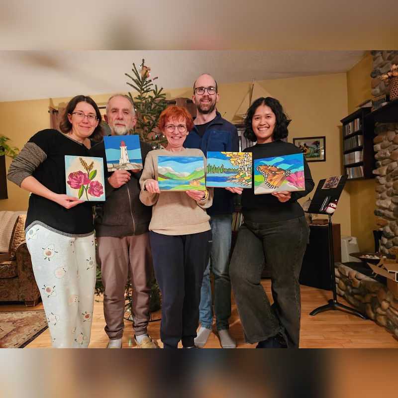 Happy Canadian family proudly displaying their finished Paint By Numbers artworks in a cozy living room. Each person holds a vibrant painting, including flowers, landscapes, a lighthouse, and a butterfly, capturing a joyful and creative moment together.