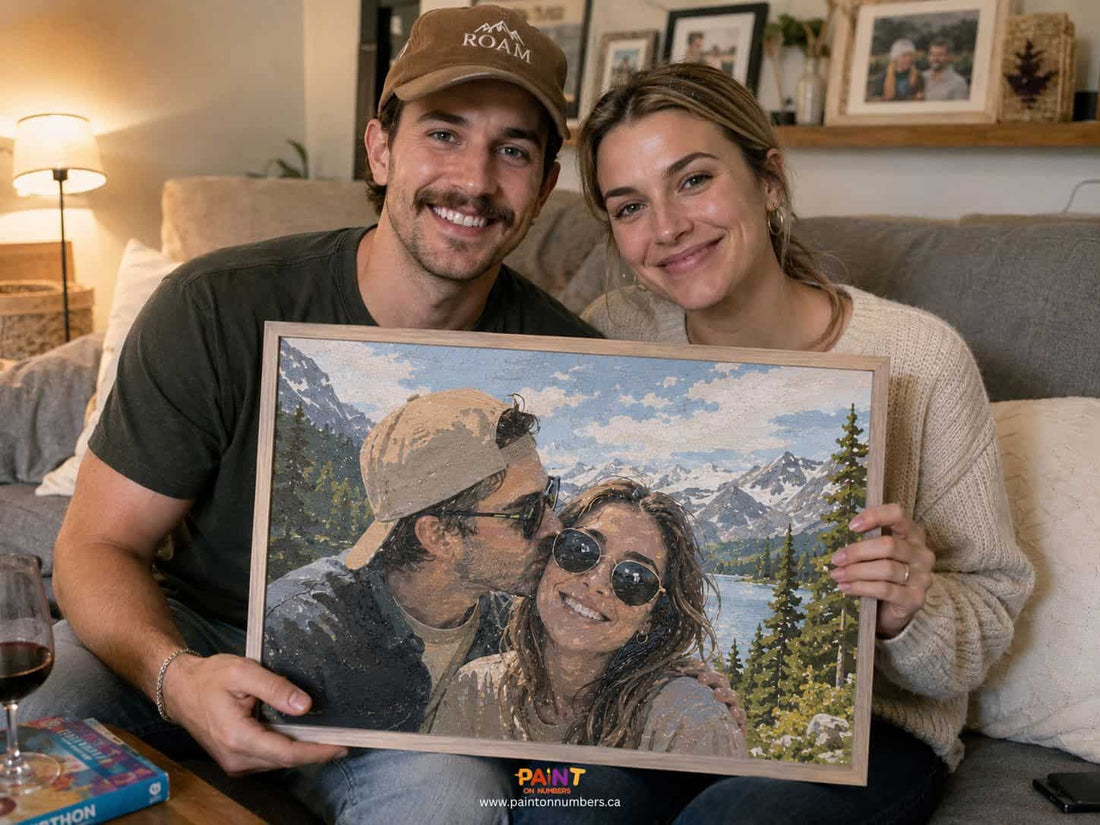 Smiling couple sitting on a couch holding a framed custom paint by numbers portrait of themselves with a mountain lake background