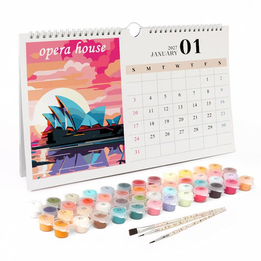 A spiral-bound desk calendar showing January 2027 with an illustrated Opera House cover page, displayed with multiple small paint pots and two paintbrushes on a white background.