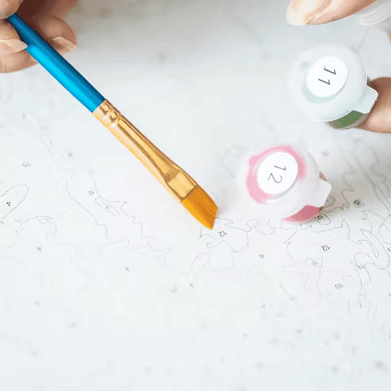 "Close-up of Paint By Numbers Kit Canada showing a flat paintbrush, numbered paint pots, and a detailed canvas with outlines"