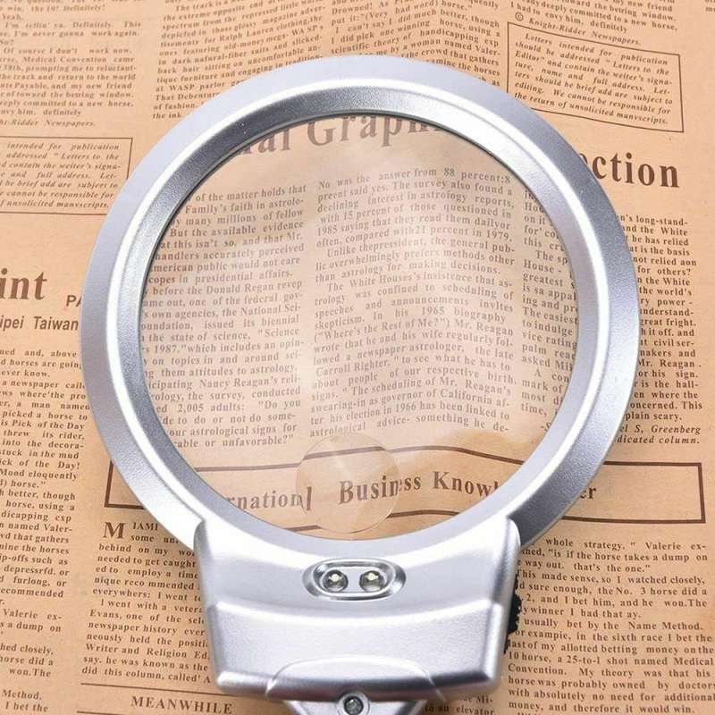 LED magnifying glass showing enlarged newspaper text through dual lens for reading and precision tasks