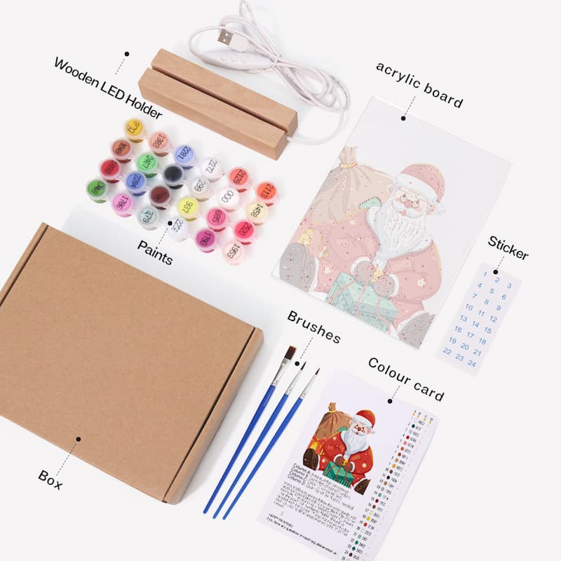 A Christmas-themed acrylic painting kit laid out on a white background, including a brown cardboard box, wooden LED light holder, white USB cable, acrylic board with Santa painting, sticker, paint pots, brushes, and a color card with labeled callouts.