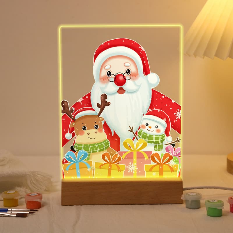 A rectangular LED light box with a wooden base displaying a festive Christmas scene. The illuminated panel shows Santa Claus, a reindeer, a snowman, and colorful gift boxes inside a glowing frame.