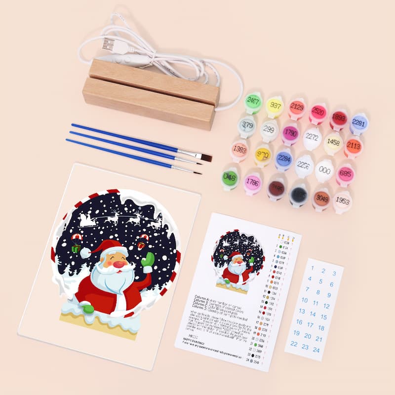Painting kit with Santa Claus design, paint bottles, brushes, and instructions on a beige background
