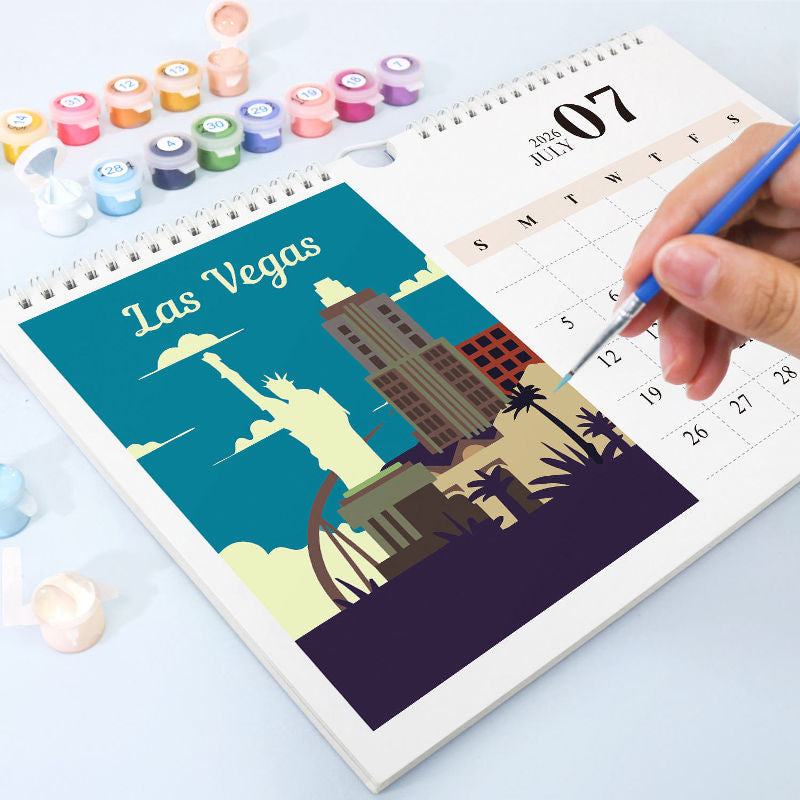 Paint by numbers wall calendar showing a Las Vegas city illustration being painted, with numbered paint pots and a hand filling color sections on the July calendar page.
