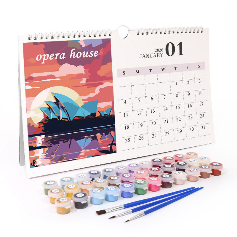 Paint by numbers calendar displayed on a tabletop with numbered acrylic paint pots and three blue-handled brushes beside an Opera House artwork page.
