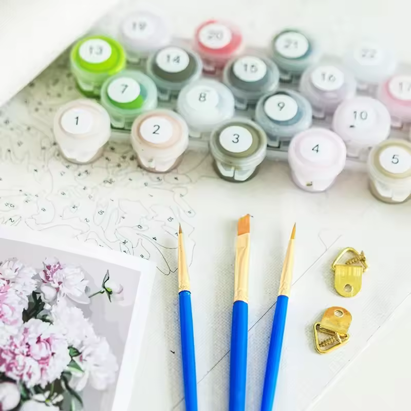 Close-up of Paint By Numbers Kit Canada, includes numbered acrylic paint pots, brushes, reference sheet, and gold canvas hangers on a pre-printed canvas