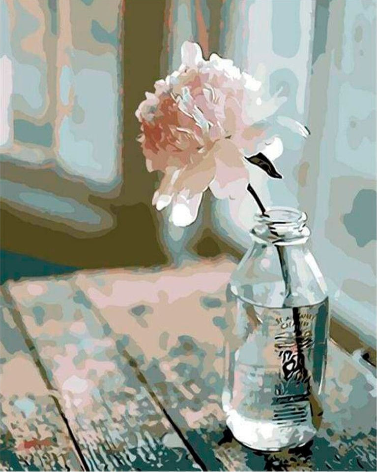 A paint by numbers painting of a white-pink rose kept in a glass bottle on a wooden table and the bottle is filled with water